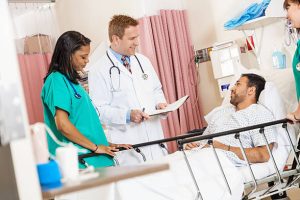 Doctor checking on injured man in hospital recovery room