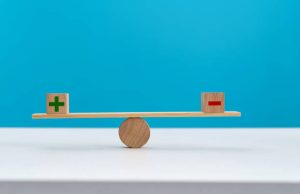 Wooden seesaw with plus and minus sign.